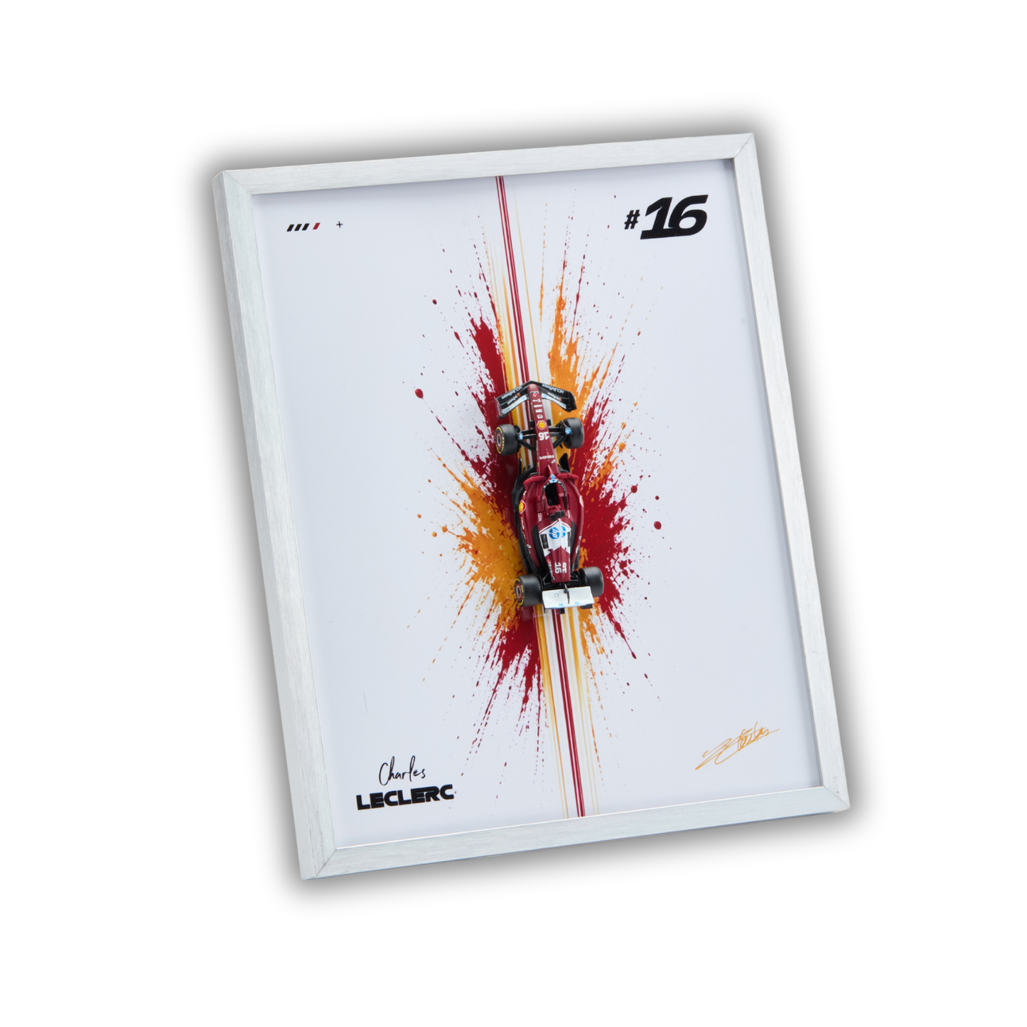 A framed wall art print featuring a red and black Formula 1 race car centered over a red and orange paint splash on a white background, with the number 16 and Charles Leclerc signatures.