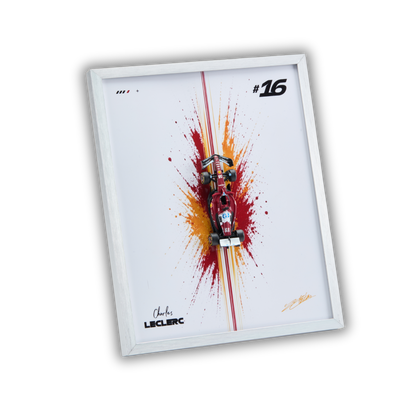 A framed wall art print featuring a red and black Formula 1 race car centered over a red and orange paint splash on a white background, with the number 16 and Charles Leclerc signatures.