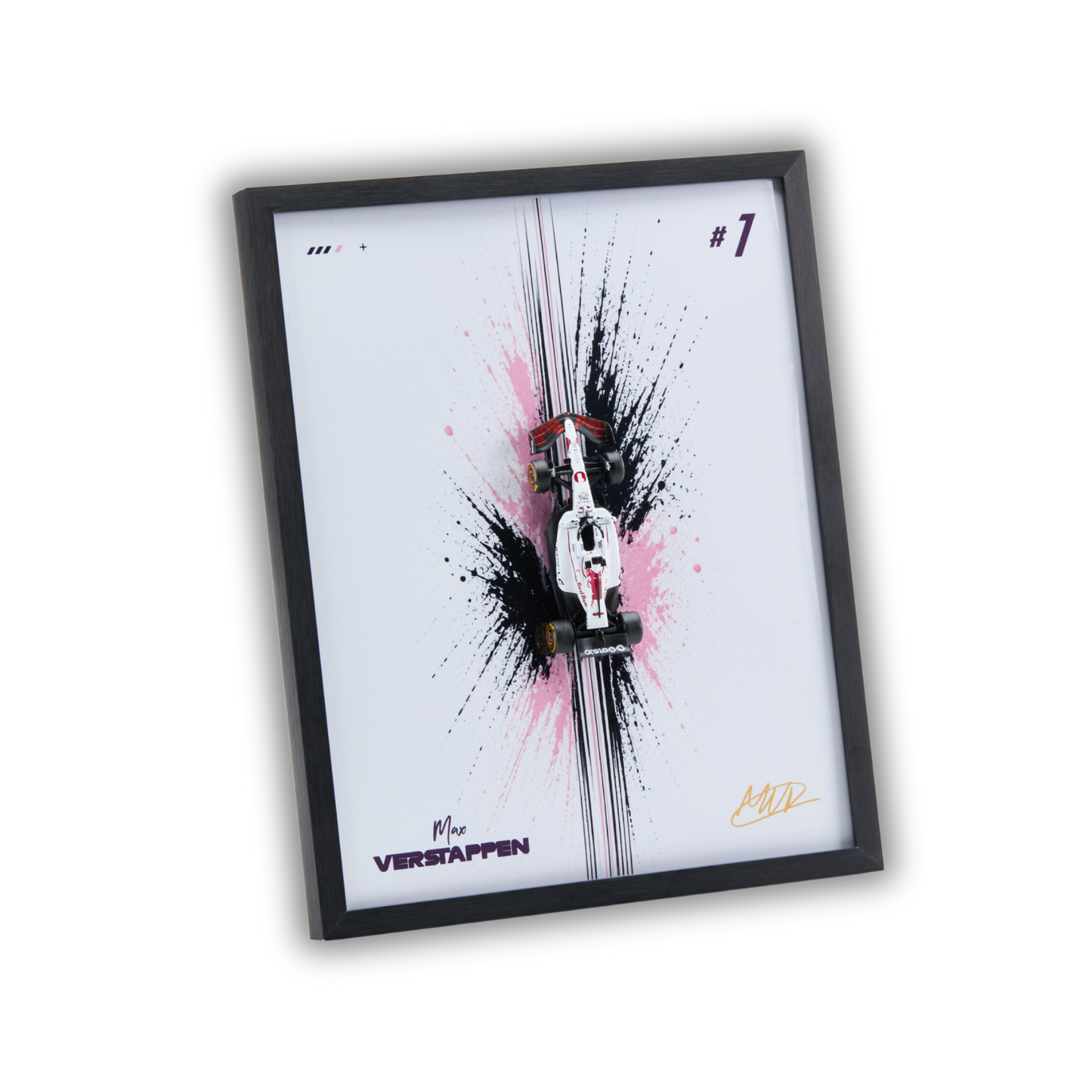 A framed art print featuring a miniature white and red Formula 1 car on a white background with black and pink paint splatters, enclosed in a black frame.