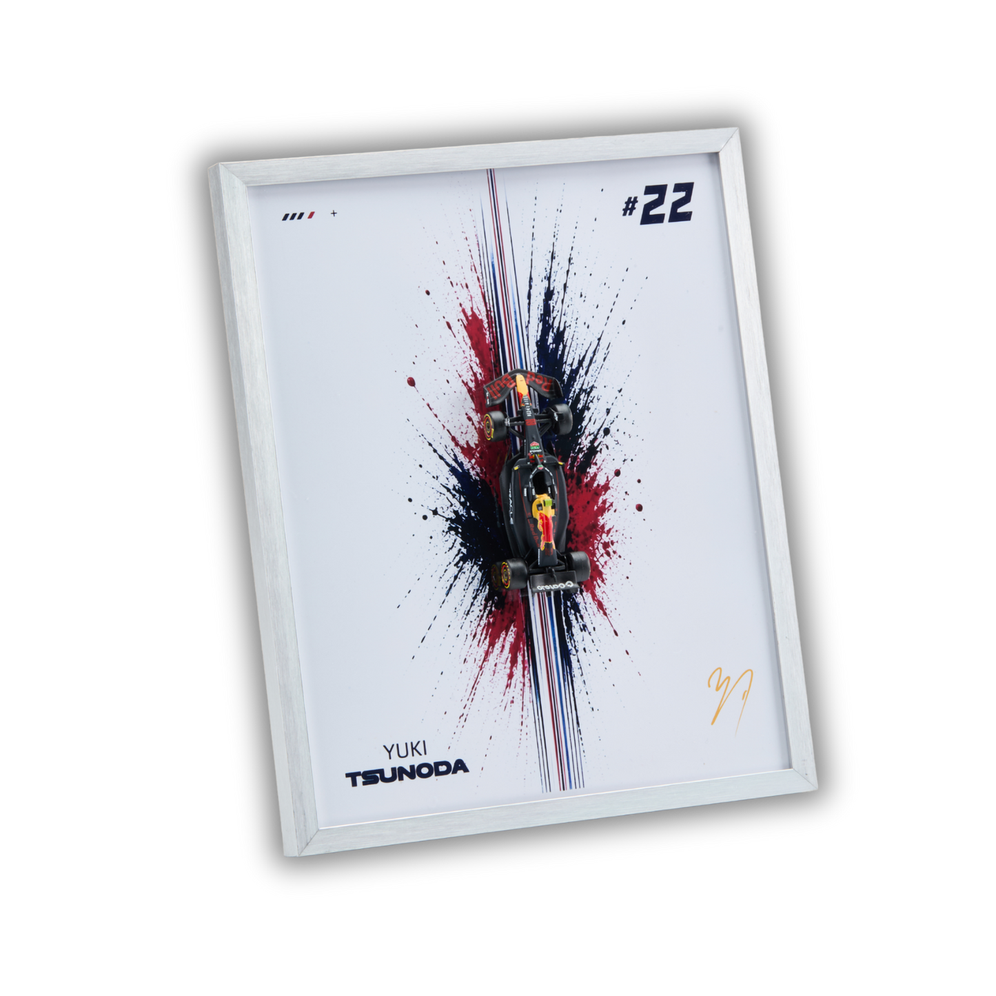 A framed art print featuring a miniature Formula 1 car on a white background with a red, black, and blue paint splatter design. The print includes the text 'YUKI TSUNODA', the number '#22', and a gold signature, all enclosed in a white frame.