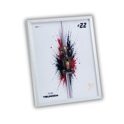 A framed art print featuring a miniature Formula 1 car on a white background with a red, black, and blue paint splatter design. The print includes the text 'YUKI TSUNODA', the number '#22', and a gold signature, all enclosed in a white frame.