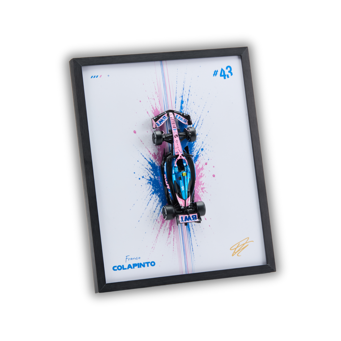 A framed wall art print featuring a pink and blue miniature Formula 1 race car mounted over a white background with paint splatter graphics. The print includes the text 'France COLAPINTO', '#43', and a gold signature, all enclosed in a black frame on a white background.