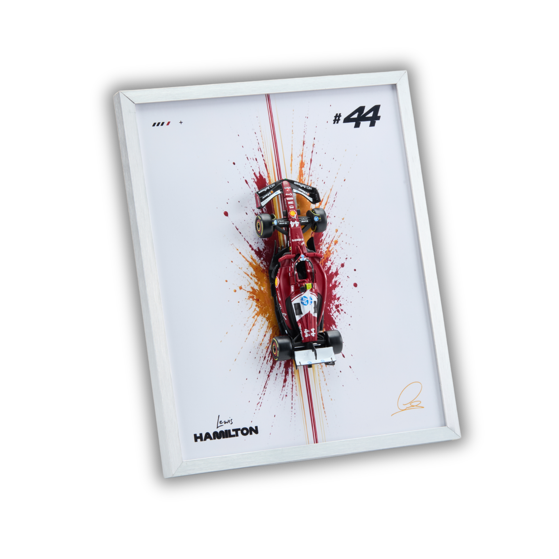 A framed wall art print featuring a red Formula 1 car on a white background with paint splatter effects, the number 44, and the name Hamilton. The print is housed in a slim white frame and shown at an angle against a clean white background.