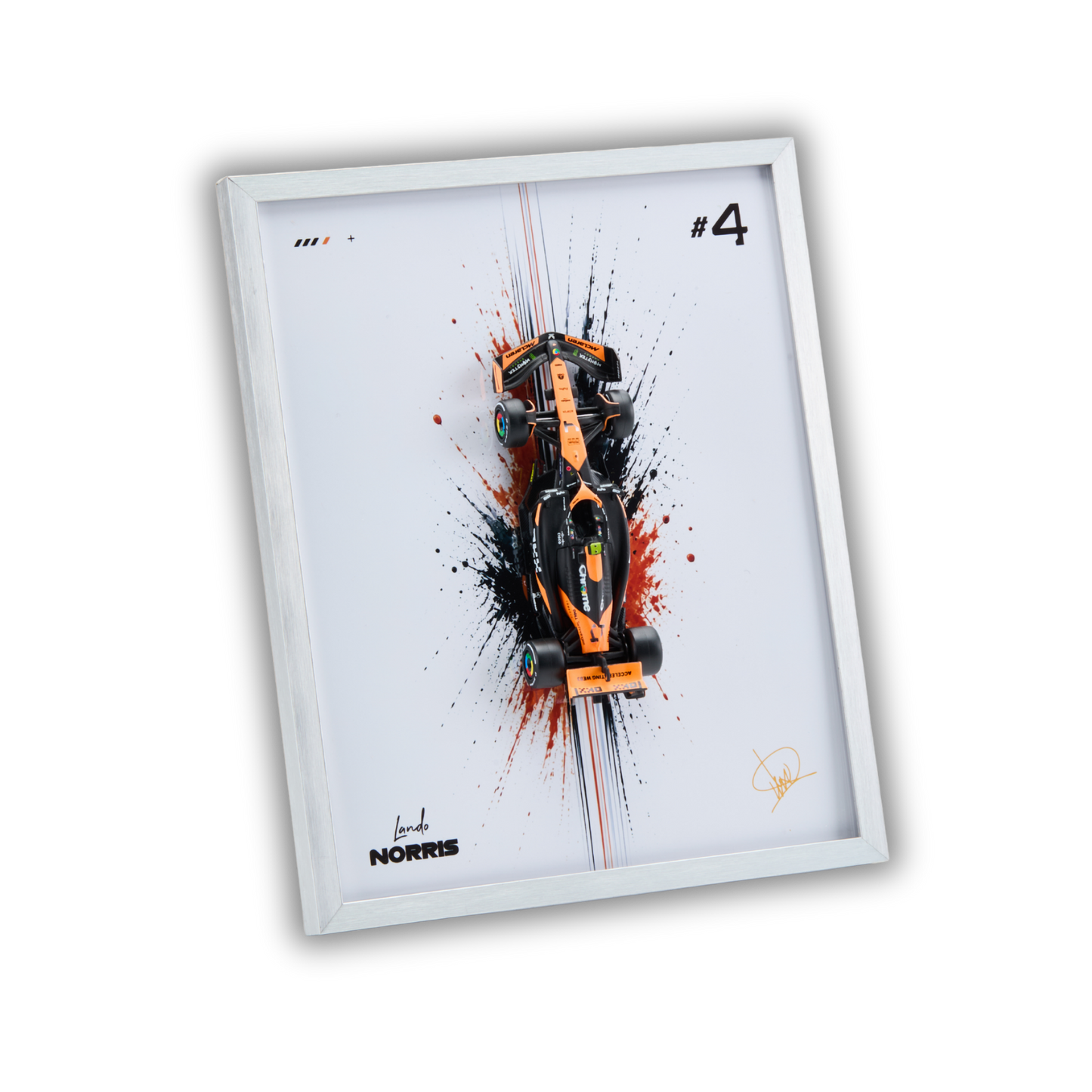 A framed art print featuring a top-down view of an orange and black Formula 1 race car over a white background with black, red, and white paint splatters. The print includes the text '#4' and 'Lando NORRIS' along with a signature, housed in a white frame.
