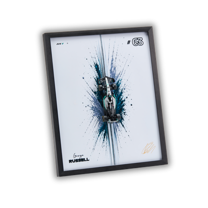 A framed wall art print featuring a stylized silver race car over a blue and black paint splatter design on a white background, with the text 'George RUSSELL' and number '63' visible. The print is housed in a slim black frame and shown at an angle against a plain white background.