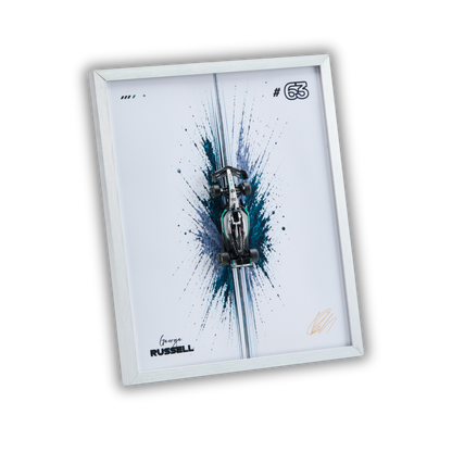 A framed art print featuring a stylized Formula 1 car emerging from blue and black paint splatters on a white background, with the number 63 and George Russell text. The print is housed in a slim white frame and shown at an angle against a black background.